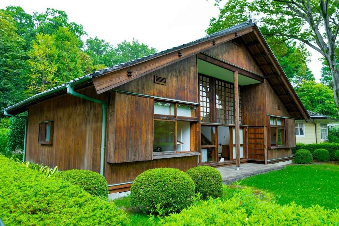 緑の庭に囲まれた、木造の平屋の外観